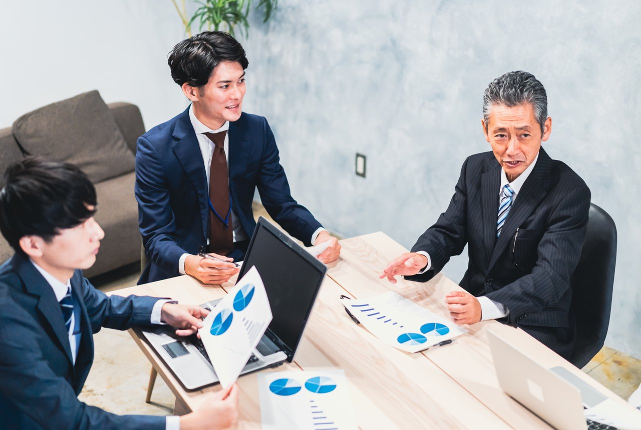 資料を広げて代理店の業務を整理する打ち合わせの様子